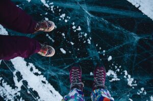 Twee paar winterlaarzen op een donker, gebarsten ijsoppervlak